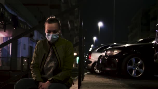 Женщина в медицинской маске на улице ночью — стоковое видео
