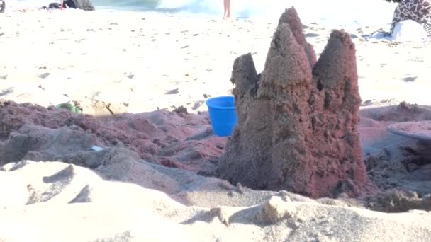 海のビーチの夏休みに砂と塔によってバックライトされます。背景に砂城と海の波 — ストック動画