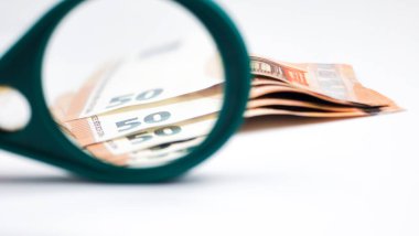 Beyaz bir masada büyüteç altında 50 Euro banknot..