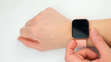 Beyaz arkaplanda akıllı bir saatin ekranına dokunan kadının eli.