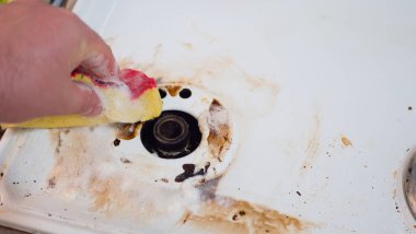 Adamın eli kirli bir gaz sobasını siliyor..