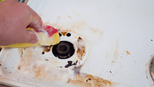 man 's hand wipes a dirty gas stove
.