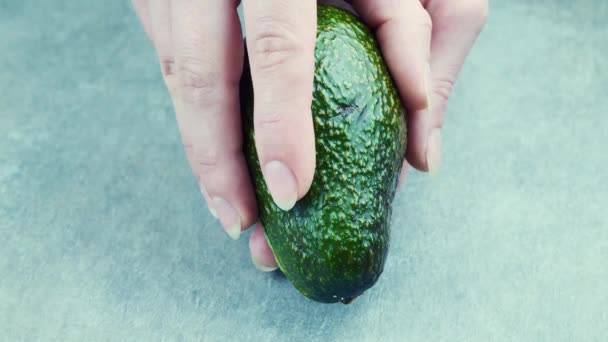 Aguacate verde dividido por la mitad en las manos en cámara lenta en 4k — Vídeos de Stock