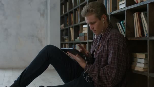 Estudiante enfocado usando tableta en la biblioteca — Vídeo de stock