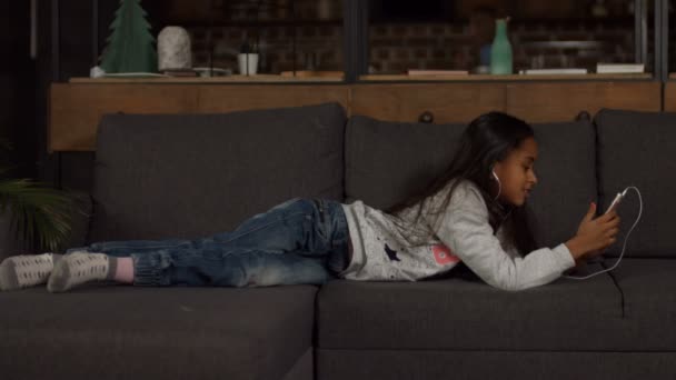 Draguta african american fata ascultand muzica pe canapea — Videoclip de stoc