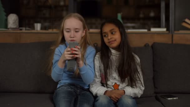 Μικρά κορίτσια στον καναπέ εναλλαγή καναλιών τηλεόρασης — Αρχείο Βίντεο
