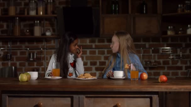 Vrolijke meisjes koekjes eten in de keuken — Stockvideo