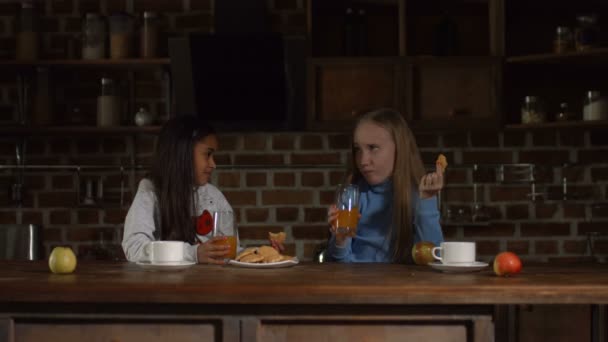 Niños comiendo galletas y bebiendo jugo en la cocina — Vídeos de Stock