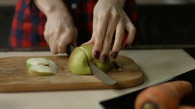 Kadın elleri kesme tahtasındaki elmayı kesiyor.