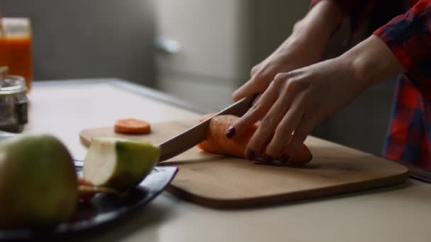 Női kezek vágás nyers sárgarépa, a vágódeszka — Stock videók