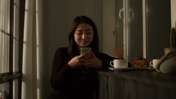 Sonriendo chica asiática escribiendo mensaje en el teléfono inteligente — Vídeo de stock