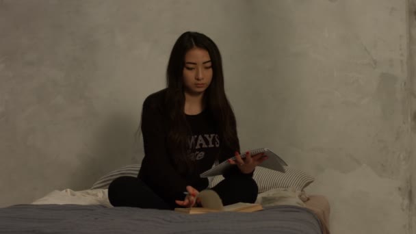 Asiática escuela secundaria chica estudiando en cama en casa — Vídeo de stock