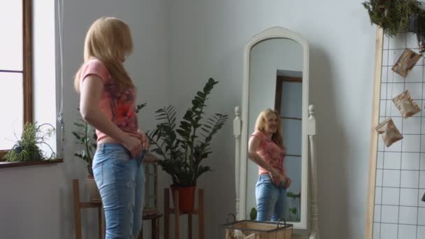 Женщина пытается втиснуться в старые джинсы — стоковое видео