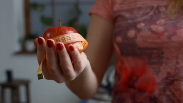 Woman holding fresh apple and measure tape — Stock Video