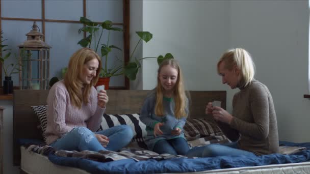 Радісна сім'я з дитиною грає в карти на ліжку — стокове відео