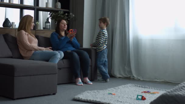 Mulheres sorrindo positivas brincando com a criança em casa — Vídeo de Stock