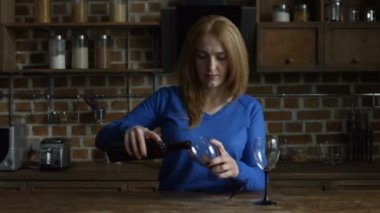 Kadın yağan kırmızı şaraba mutfakta gözlük