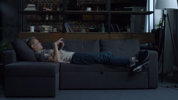 デジタル タブレットのソファに横たわっているカジュアルなティーンエイ ジャー — ストック動画