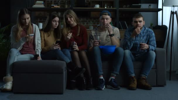 Група молодих друзів дивиться спортивне телебачення вдома — стокове відео