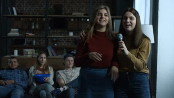 Радісні дівчата співають караоке в домашній кімнаті — стокове відео