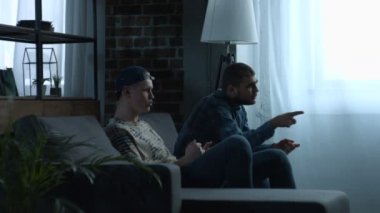 Genç erkekler evde spor TV izlerken heyecanlı.