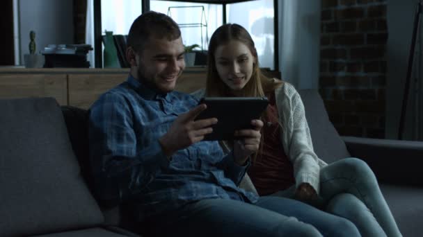 Jeune couple souriant avec tablette relaxante sur canapé — Video