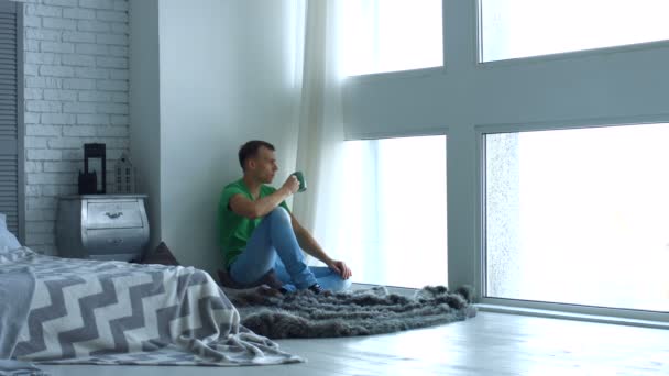 Junger Mann genießt Morgenkaffee am Fenster — Stockvideo