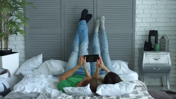 Расслабленная пара с цифровым планшетом на кровати — стоковое видео