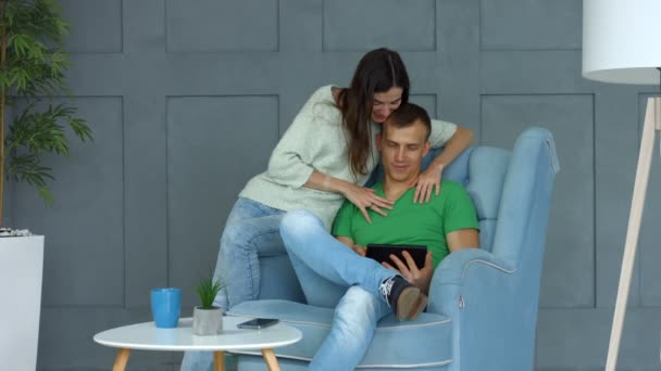 Случайная пара обмена планшетным ПК сидя на кресле — стоковое видео