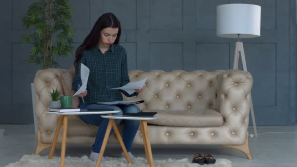 Stressed young woman doing home accouting on sofa — Stock Video