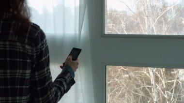 Güzel kadın pencere yakınındaki akıllı telefon arama