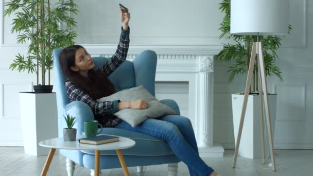 Mujer sonriente tomando selfie en el teléfono inteligente en casa — Vídeos de Stock