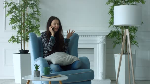 Mulher alegre em poltrona conversando no telefone inteligente — Vídeo de Stock