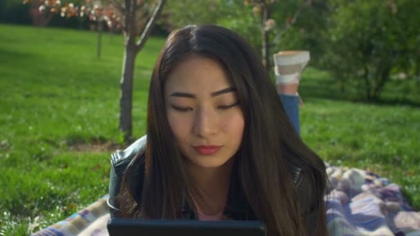 Encantadora chica asiática con tableta pc en el parque de primavera — Vídeos de Stock