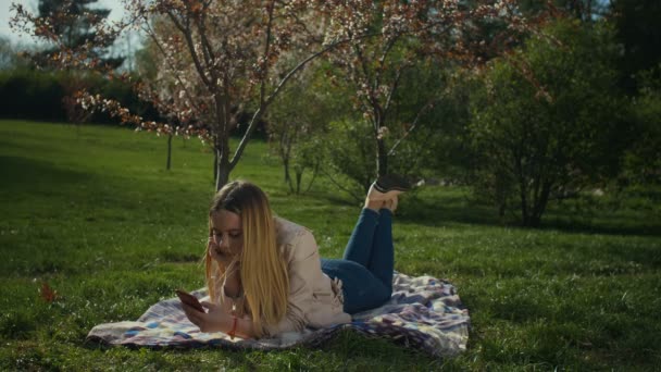 Linda chica charlando en línea en el teléfono inteligente en el parque — Vídeo de stock