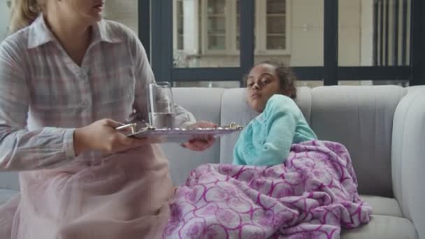 Заботливая мать дает таблетки и воду больному ребенку — стоковое видео