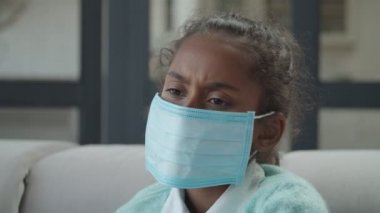 İçeride maske takan üzgün hasta bir kız.