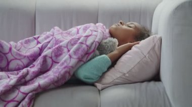 Küçük tatlı siyah kız kanepede oyuncakla uyuyor.