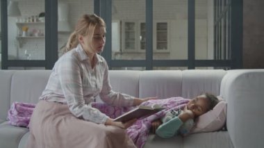 Sevimli anne kanepede tatlı çocuğa kitap okuyor.