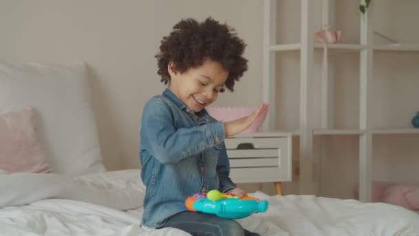 Joyful kid playing with toy steering wheel indoors — Stock Video