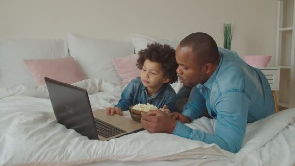 Familj med popcorn streaming film online på sängen — Stockvideo