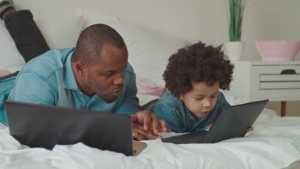 Cuidar negro papá enseñando hijo usando portátil en casa — Vídeos de Stock