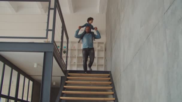 Dad piggybacking son going downstairs at home — Stock Video