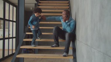 Küçük tatlı çocuk merdivenlerde cep telefonuyla konuşuyor.