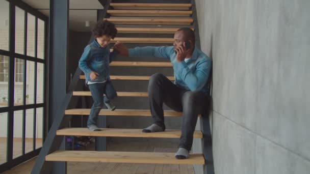 Krásný malý chlapec mluví na mobilu na schodech — Stock video
