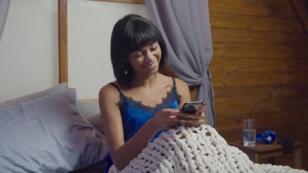ベッドの中でスマートフォンと正の女性ネットワーク — ストック動画
