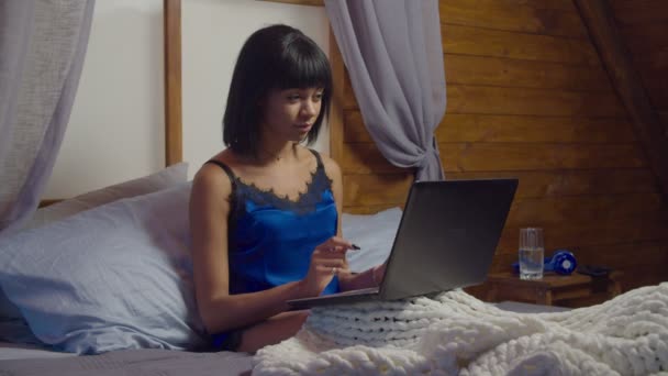 Mooie vrouw in pyjama werken op laptop in bed — Stockvideo