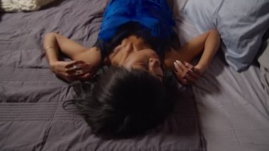 Yorgun bir kadın gece yatağa düşüyor.