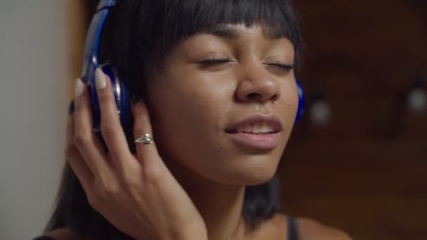 Alegre mujer escuchando música en auriculares en casa — Vídeos de Stock