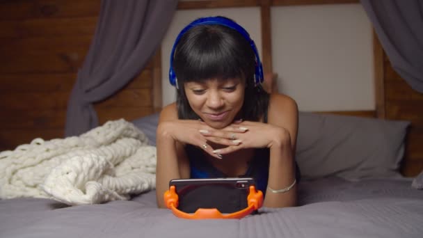 Симпатичная женщина потокового видео онлайн по телефону на кровати — стоковое видео